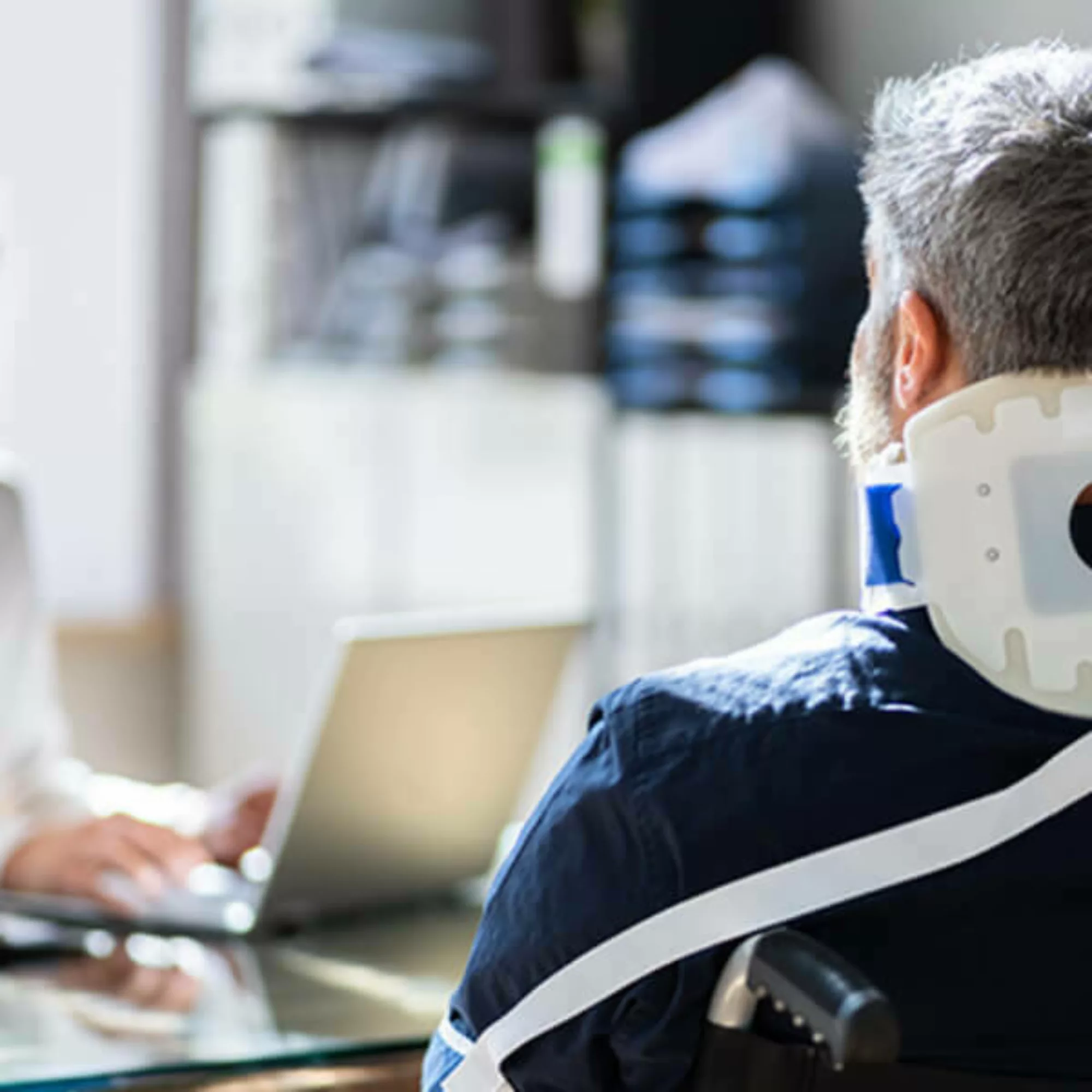 Injured worker with a neck brace sitting in front of an attorney's desk.