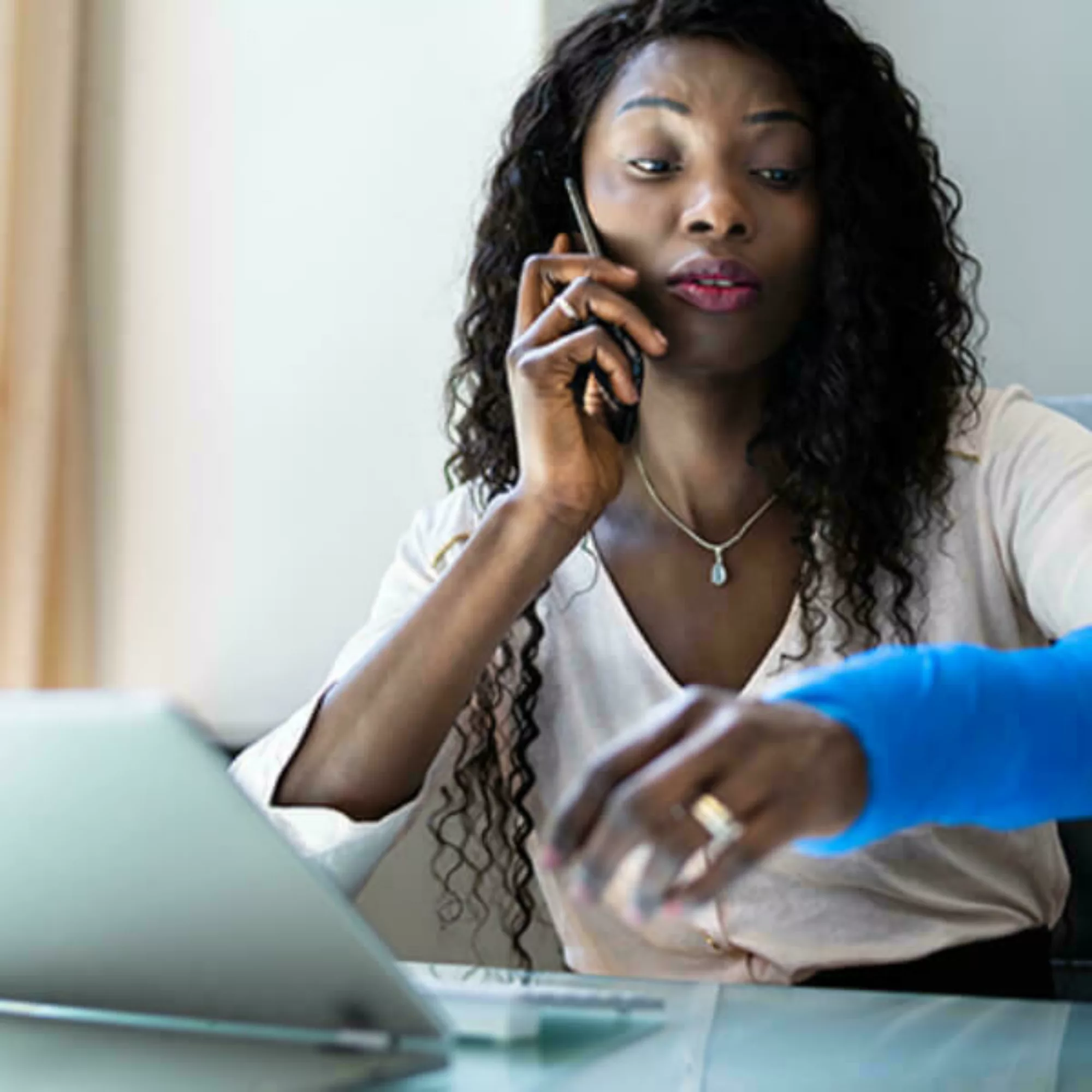 Woman on the phone sitting at a computer.