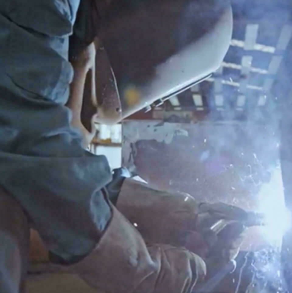 Welder working with mask and gloves on.