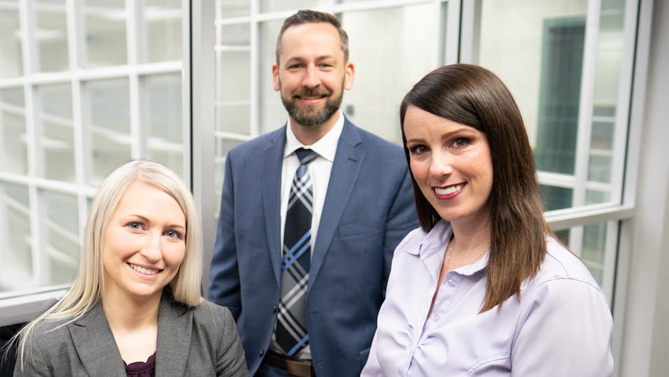 Three Black & Jones team members smiling in their office.