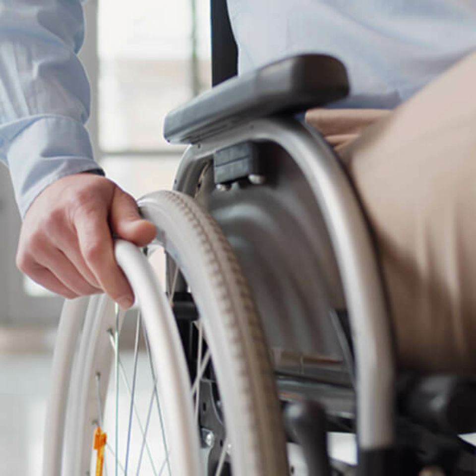 Close up of hand turning the wheel of a wheelchair.