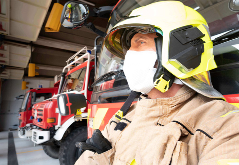 firefighter in mask infront of fire engines