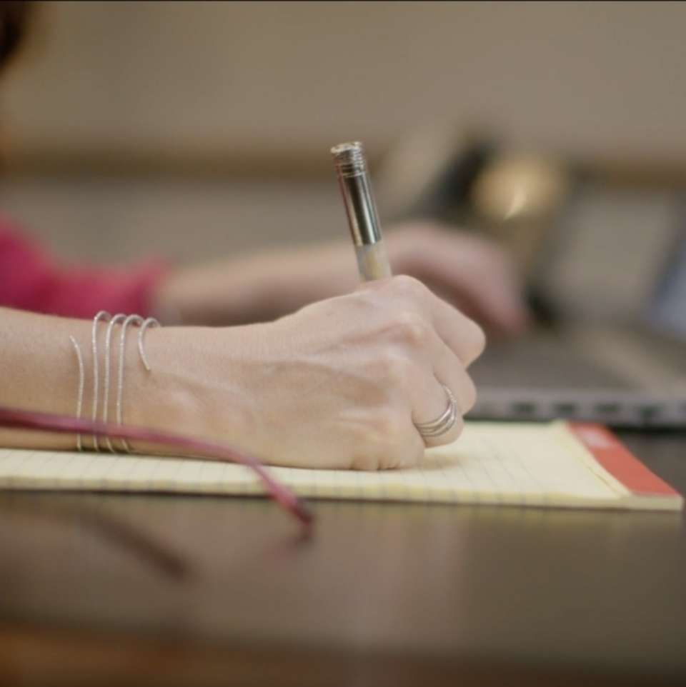 female hand writing on notepad