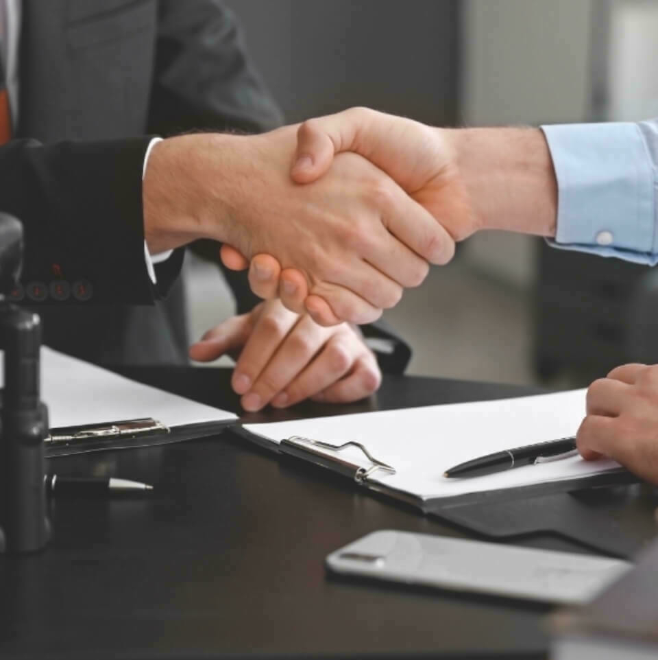 Two people shaking hands over a table.