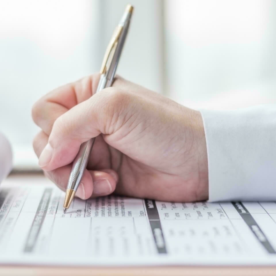 Close up of a hand filling out forms.