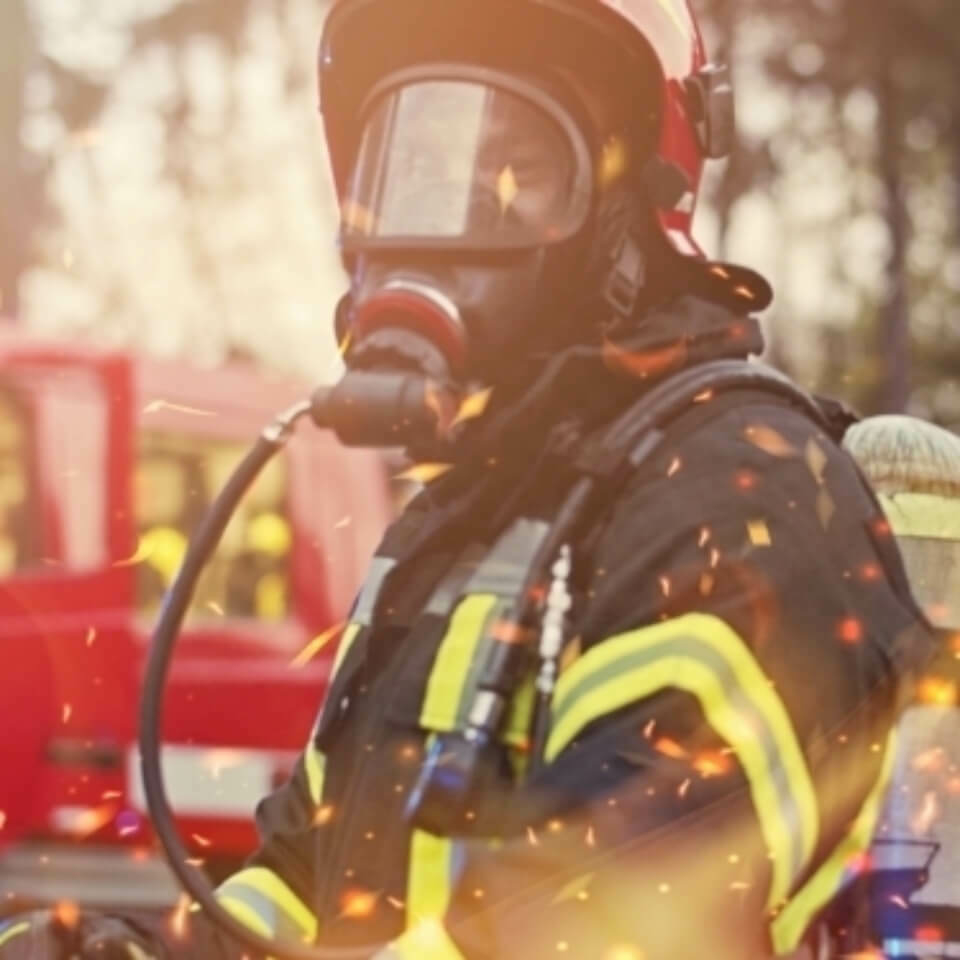 Firefighter among sparks in front of a fire truck.