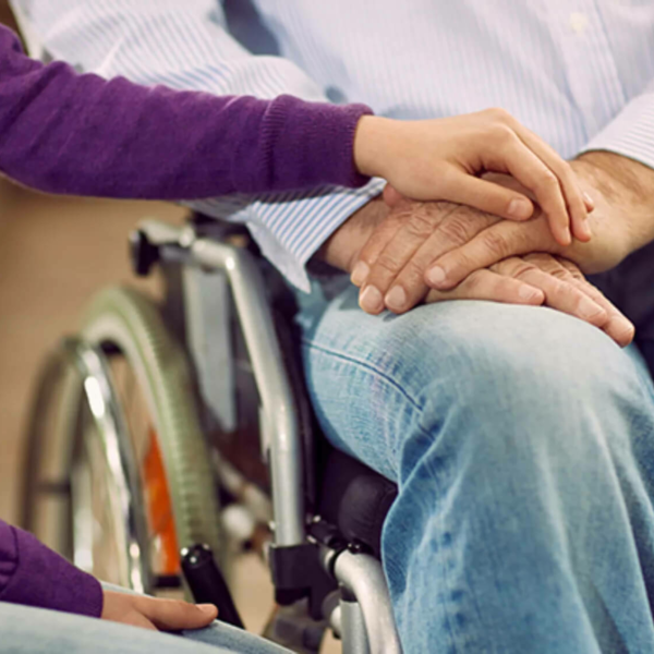 Hands embraced in the lap of a person in a wheelchair.