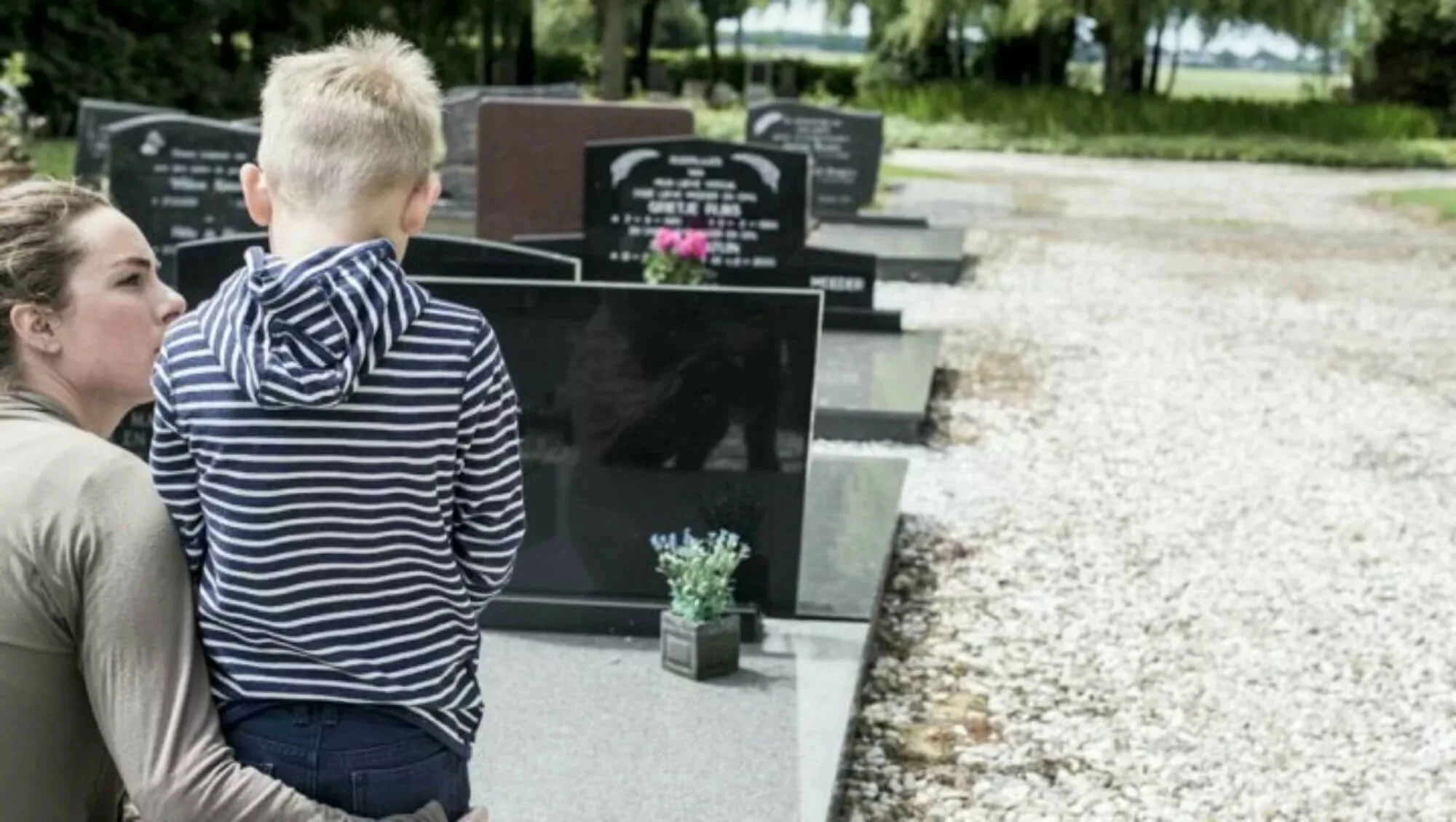 Child kneeling in front of a grave.