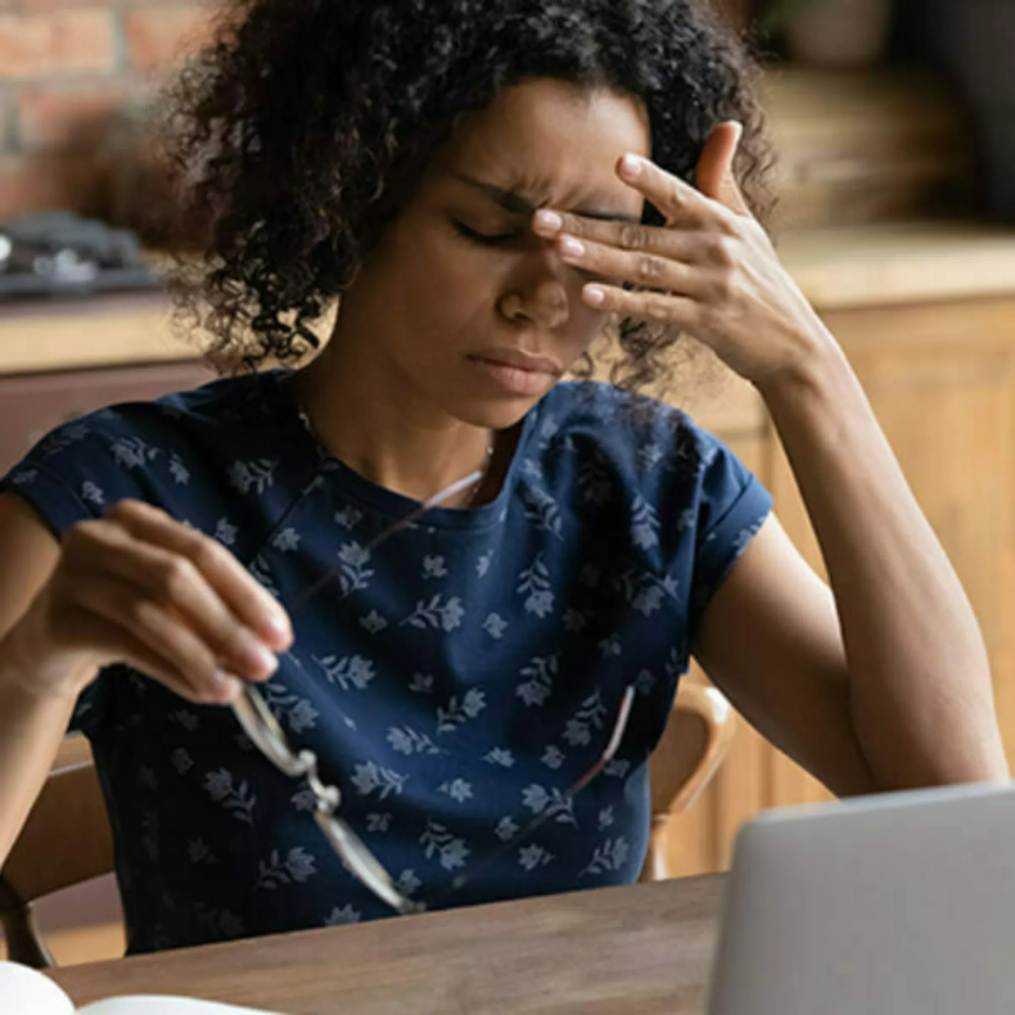 woman sitting at desk rubbing forehead