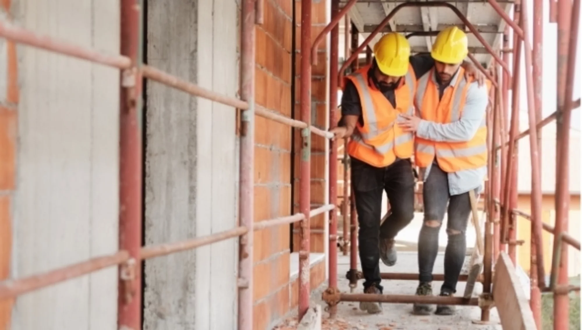 Injured construction worker being held up by another worker.