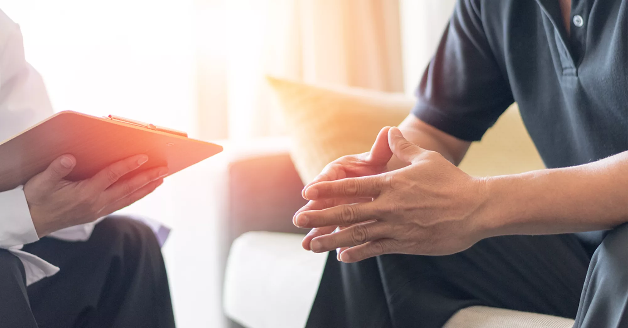 Close up of hands clasped in man's lap.