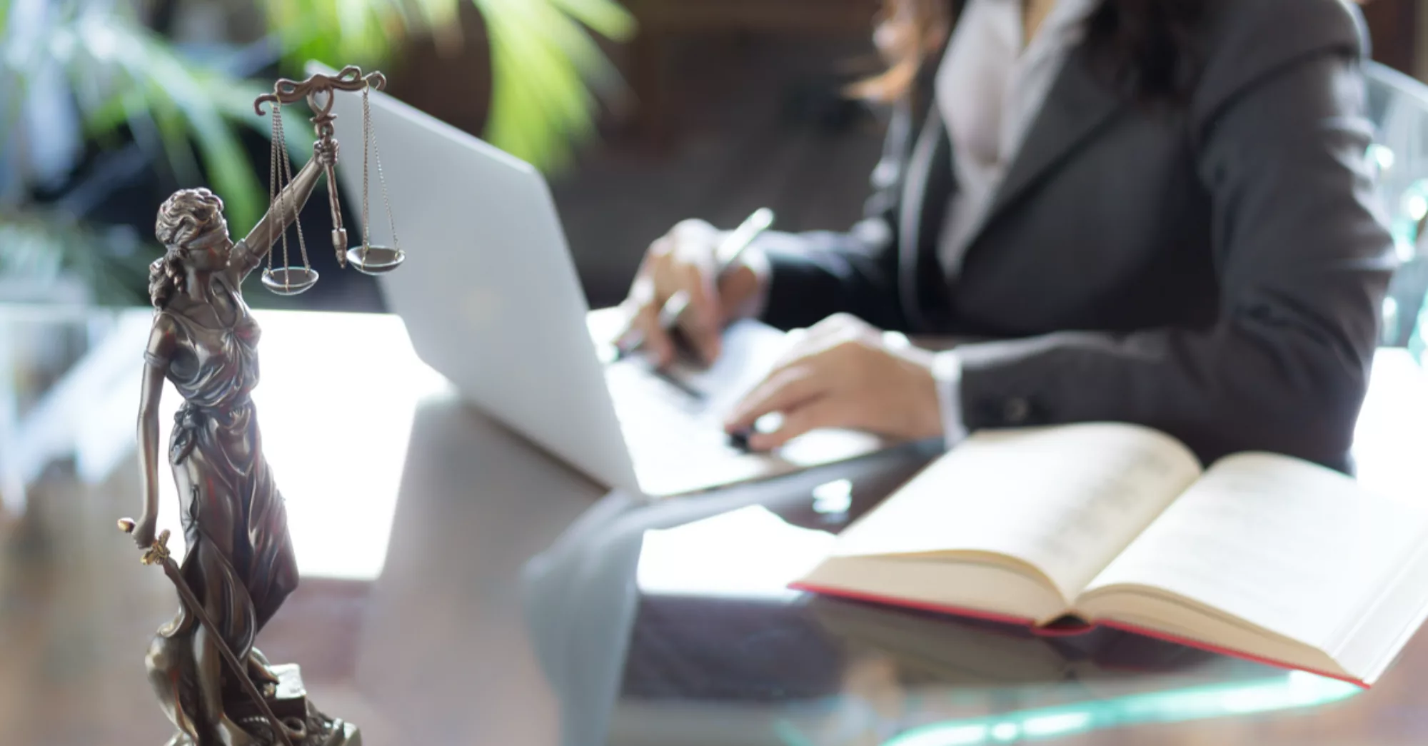 Attorney working at desk with a lady justice statue.