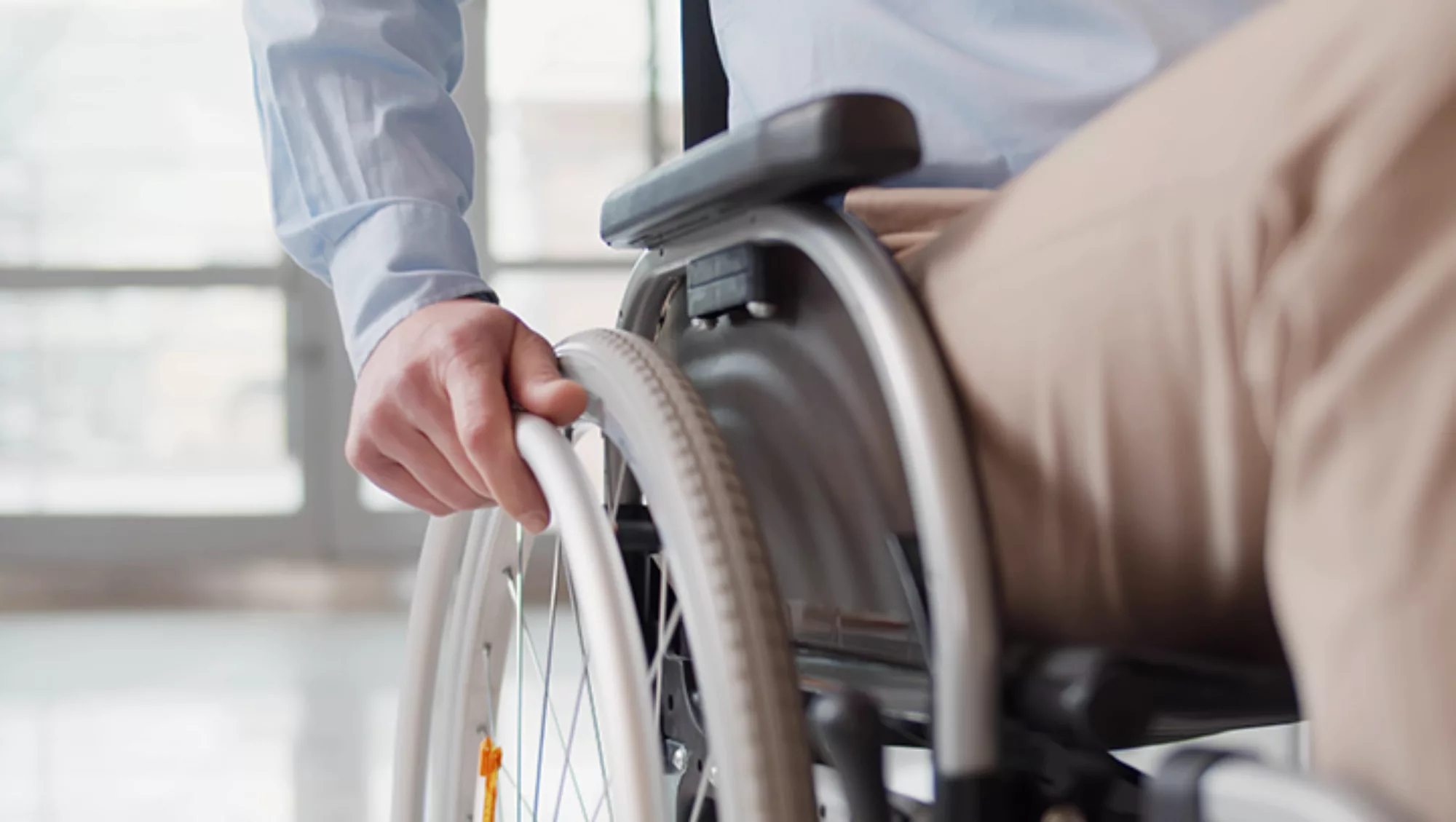 Close up of hand turning the wheel of a wheelchair.