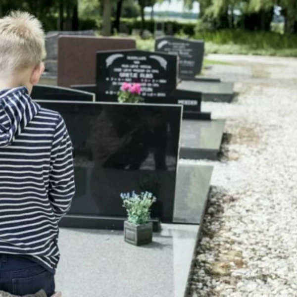 Child kneeling in front of a grave.